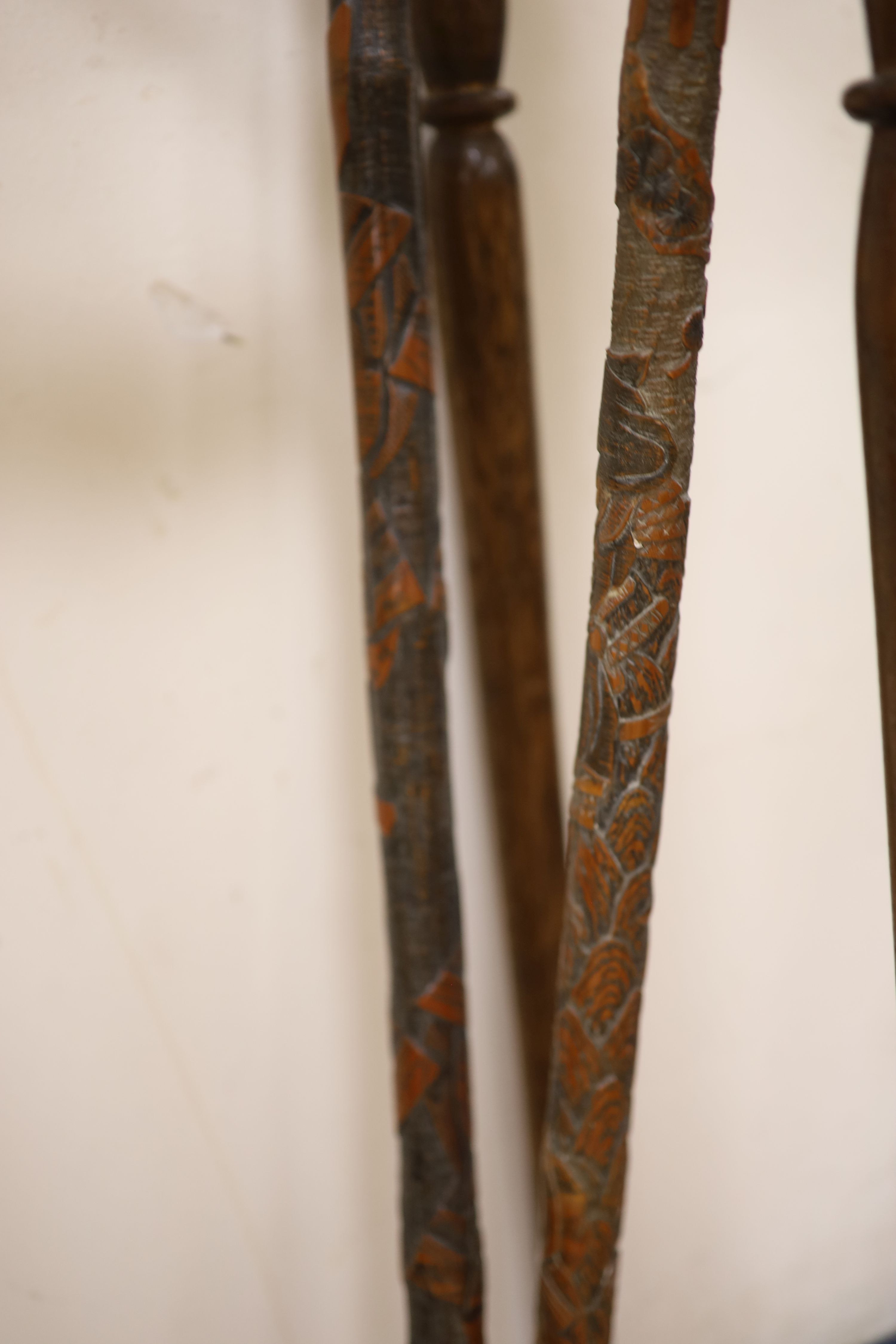 Four Chinese carved wood walking canes, together with a stick stand